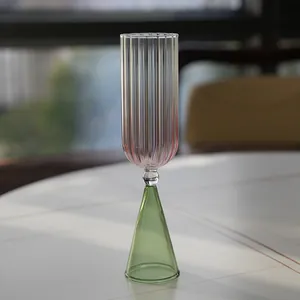 Detalle de una copa de postre creativa de vidrio estriado con base cónica verde en una mesa