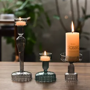 Three elegant smoke grey striped glass candle holders with lit candles on a wood table.