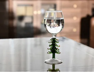 Verre à vin élégant avec une tige en forme de sapin de Noël vert et décorations rouges