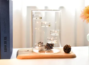 Cozy home decor detail showing a multi-tier glass candle holder with pinecones on wood tray