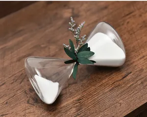 Close-up of a Nordic glass hourglass with white sand and dried flower decor on wood