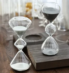 Detalle de un creativo reloj de arena de vidrio de tres niveles con arena blanca y negra.