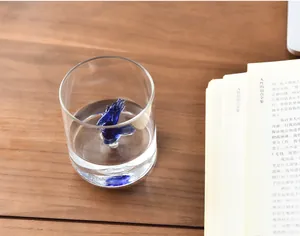 Close-up of a creative 3D blue bird glass sculpture inside a clear drinking cup