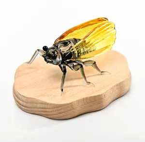 Macro view of handcrafted glass cicada figurine with golden amber wings on wood