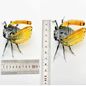 Detailed view of glass cicada figurine with ruler showing length and width dimensions.