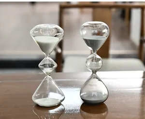 Primer plano de dos relojes de arena creativos de vidrio de tres capas con arena blanca y gris