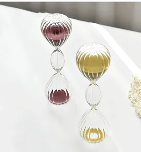 Nahaufnahme von eleganten dreischichtigen gestreiften Glassanduhren mit lila und gold sand