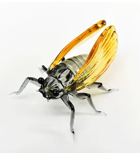 Detailed macro shot of a handcrafted glass cicada ornament with amber wings.