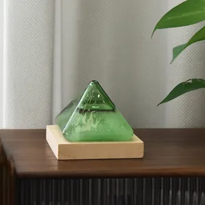 Green pyramid storm glass weather predictor station on a wooden base for creative home decor