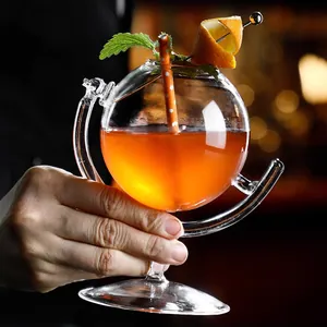 Elegante copa de cóctel con forma de globo sostenida a mano en un bar profesional