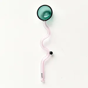 Close-up of pink wavy glass coffee stirrer with a green round head and 'LOVE' text