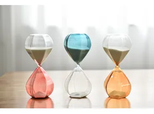 Macro view of three elegant decorative glass hourglasses with colorful sand on a table