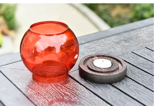 Close-up of a elegant red glass candle holder with wooden base on a rustic table