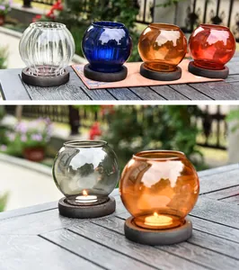 Detailed macro view of multi-colored glass candle holders with lit tea light candles on wooden bases
