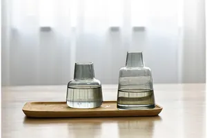 Close-up detail of smoky grey glass vases on a wooden tray for minimalist Nordic home decor