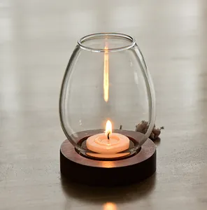 Detail of vintage glass candle holder with wooden base and flickering tea light candle