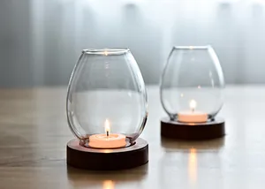 Close-up of elegant glass candle holders with wooden bases and lit tea lights