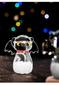 Détail d'un verre tempête en forme de chat avec des ailes de chauve-souris et un collier rouge