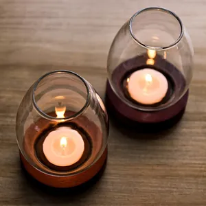 Pair of vintage transparent glass candlesticks with wooden bases on a wooden table