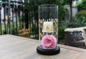 Elegant glass candle holder featuring a pink rose and festive gold tree patterns on a table