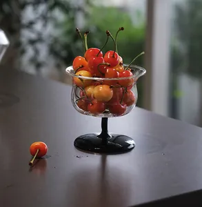 Elegante copa de postre con forma de campana llena de cerezas en mesa oscura