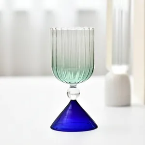 Detail of creative ribbed glass goblet with green gradient and blue conical base.