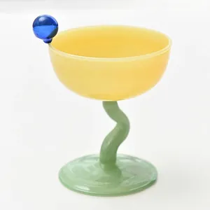 Elegante coppa da dessert in vetro giallo con stelo verde e sfera blu decorativa
