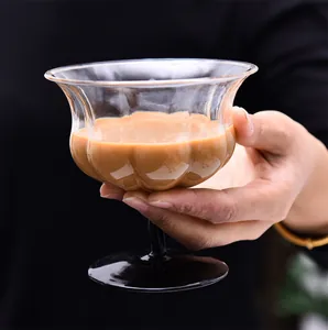 Detalle de una copa de postre de cristal con forma de lirio y tallo negro en la mano