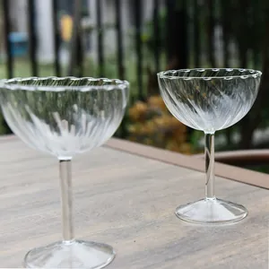 Elegant ribbed glass champagne coupe goblets on a wooden outdoor table