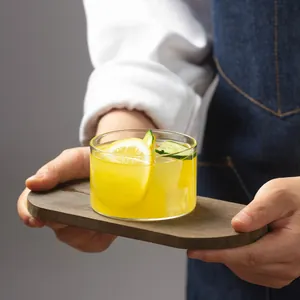 Gros plan d'un bol à dessert minimaliste en verre transparent sur un plateau en bois.