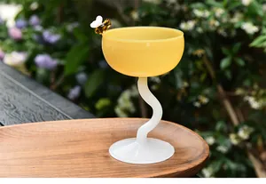 Detailed macro view of a yellow glass dessert cup with wavy stem and bee ornament