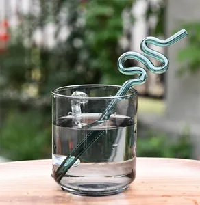 Primer plano de una pajita decorativa de vidrio en espiral verde en un vaso de agua