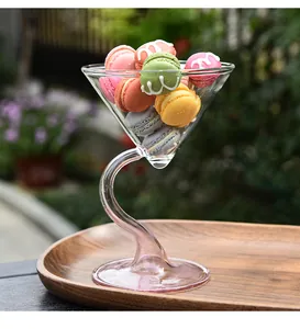 Close-up van een creatief glas met gebogen steel met kleurrijke macarons in de buitenlucht.