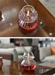 Detail view of a vintage handmade transparent glass oil lamp with a warm lit flame