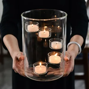 Elegant large cylindrical glass candle holder with multiple lit tea lights for decor