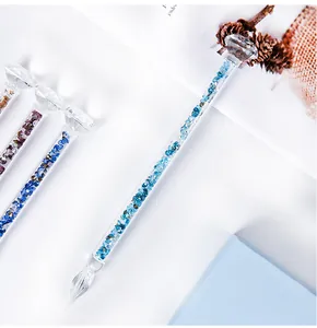 Detailed view of elegant glass dip pen filled with sparkling blue crystals and diamond top