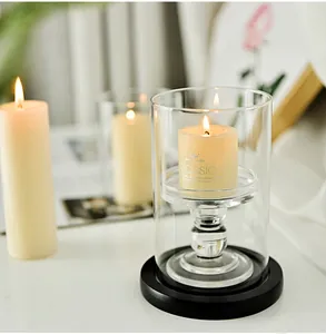 Close-up of a clear glass candle holder with a classic pillar candle on a black base