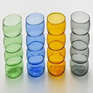 Set di quattro bicchieri in vetro ondulato colorati in verde, blu, ambra e grigio.