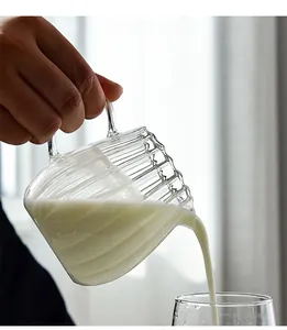 Action shot of milk pouring from a minimalist ribbed glass creamer into a glass