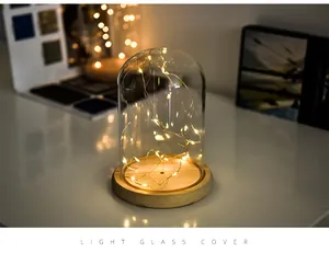 Close-up of decorative glass dome with warm LED fairy lights on a wooden base