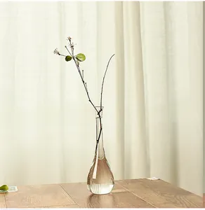 Detailed view of a slender Japanese-style clear glass vase on a wooden table.