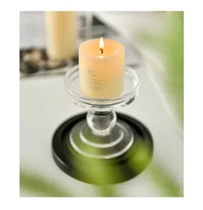 Close-up detail of a burning pillar candle inside a decorative transparent glass holder