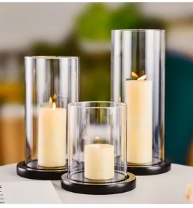 Close-up of three glass hurricane candle holders with warm lit candles on wooden bases