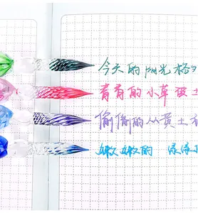 Detail of colored glass dip pen nibs with handwritten ink samples on paper