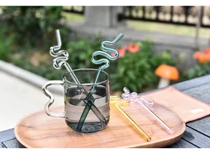Vista detallada de pajitas de vidrio coloridas en espiral en un vaso de agua clara