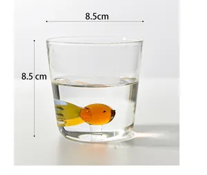 Macro detail of a minimalist glass cup with a 3D amber fish and 8.5cm dimensions.