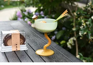 Unique wavy orange stem glass dessert bowl for ice cream in a scenic outdoor garden