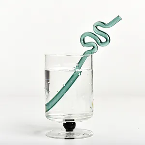 Pajita creativa de vidrio ondulado verde en una taza de cristal para zumos y jugos