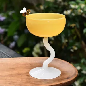 Creative yellow glass dessert cup with bee decoration on wooden tray