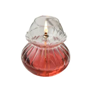 Vintage handmade ribbed glass oil lamp with a lit flame on a clean white background